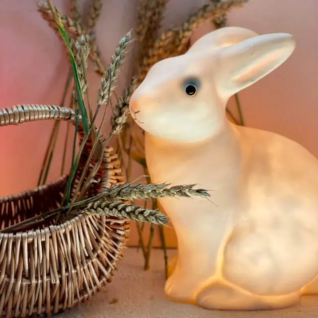 Brandende witte Egmont Toys konijnenlamp naast een rieten mand met droogbloemen