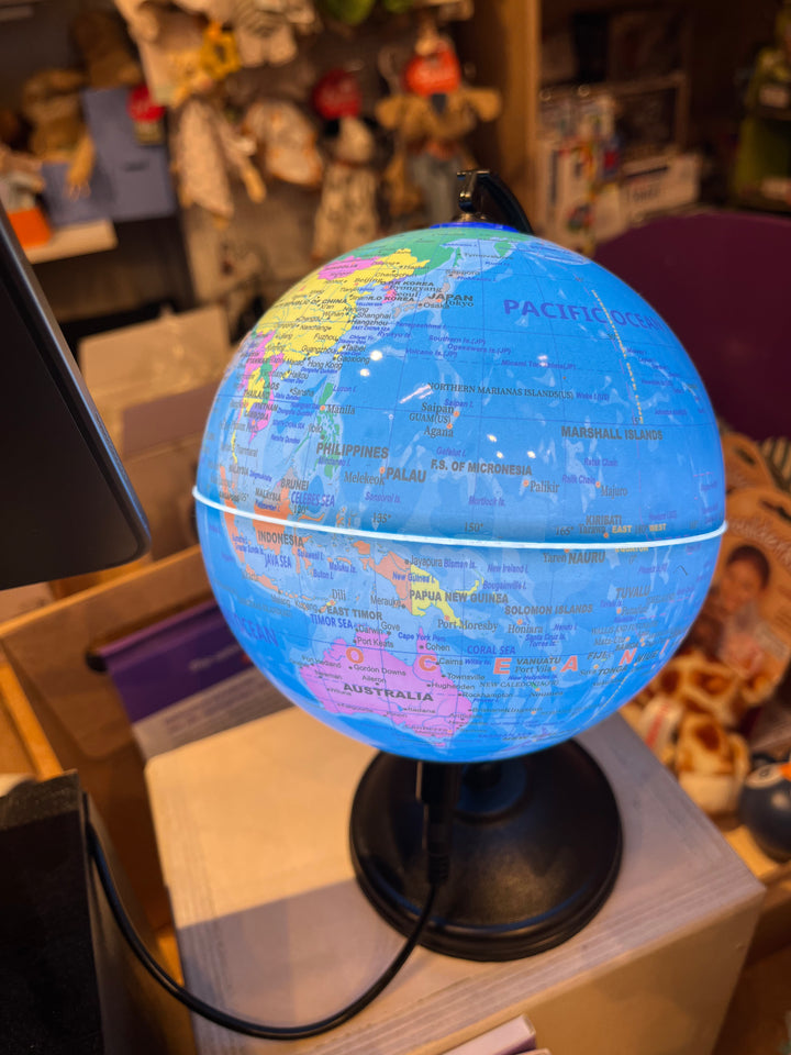 Verlichte blauwe wereldbol tafellamp op zwarte voet in de winkel