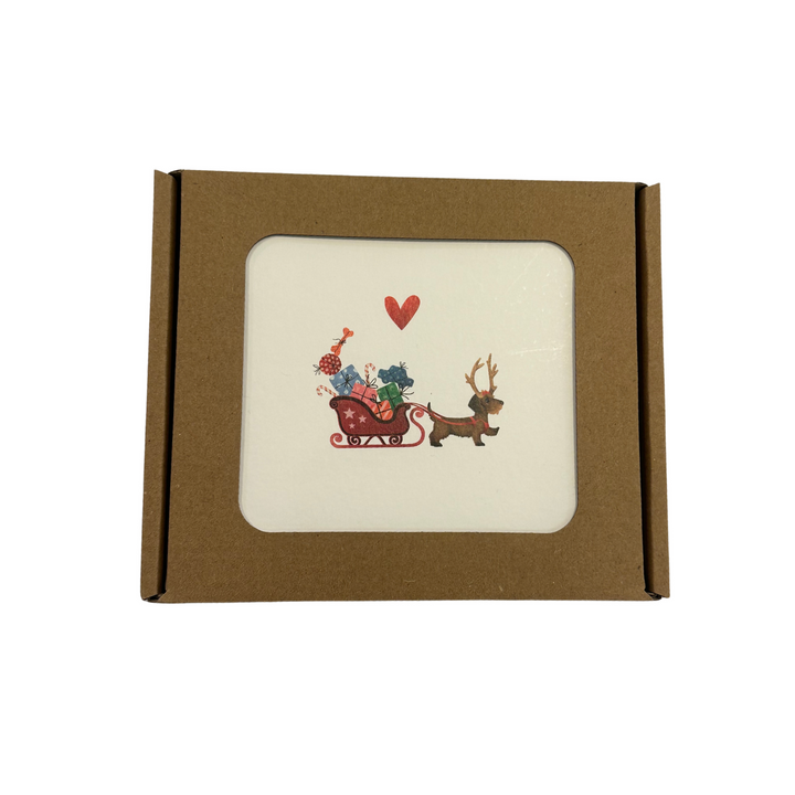 Boîte de Noël Yon 5 avec un teckel tirant un traîneau de cadeaux et un cœur rouge sur la carte du dessus