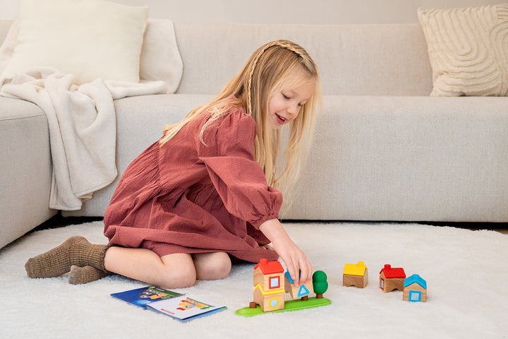 A child plays with the wooden houses of Stapel Dorp on the floor