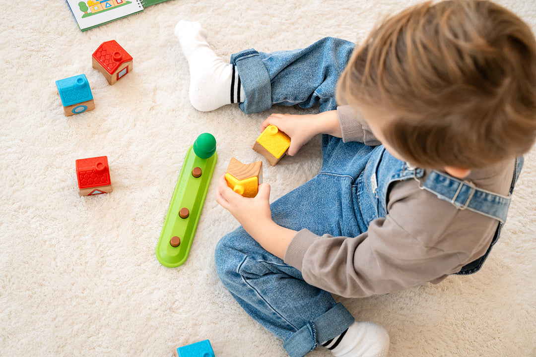 A child’s hands build with the house blocks of Stapel Dorp