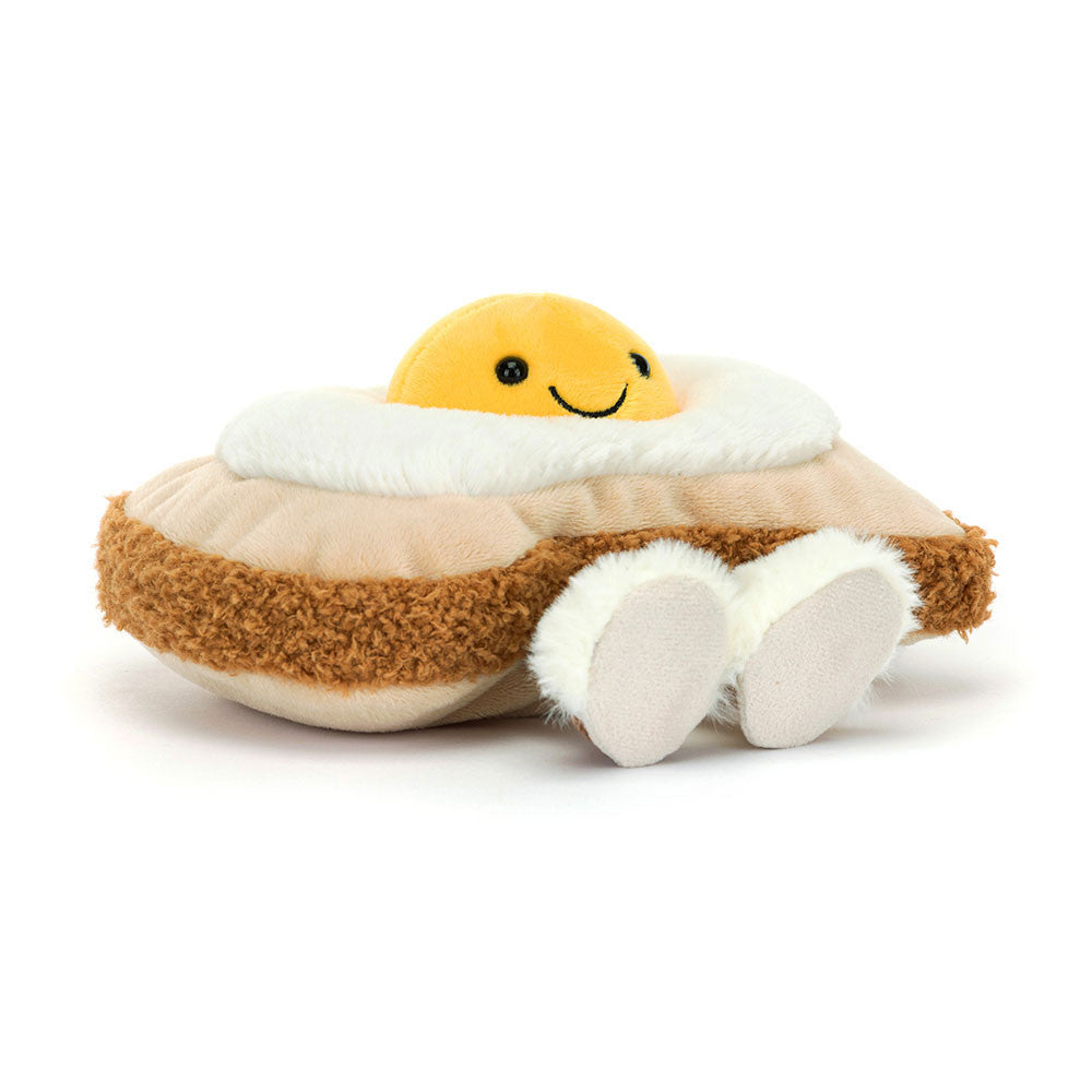 Jellycat Egglantine Egg On Toast mit gelbem Eigelb, brauner Kruste und cremefarbenen Hausschuhen, schräg von vorn