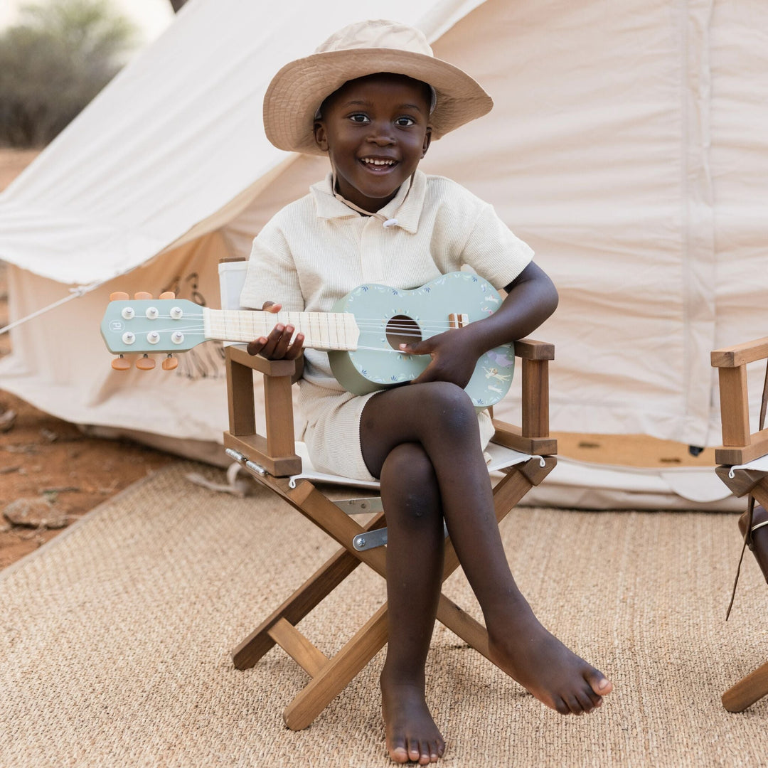 Kind speelt buiten op de groene Little Dutch Safari Friends houten gitaar