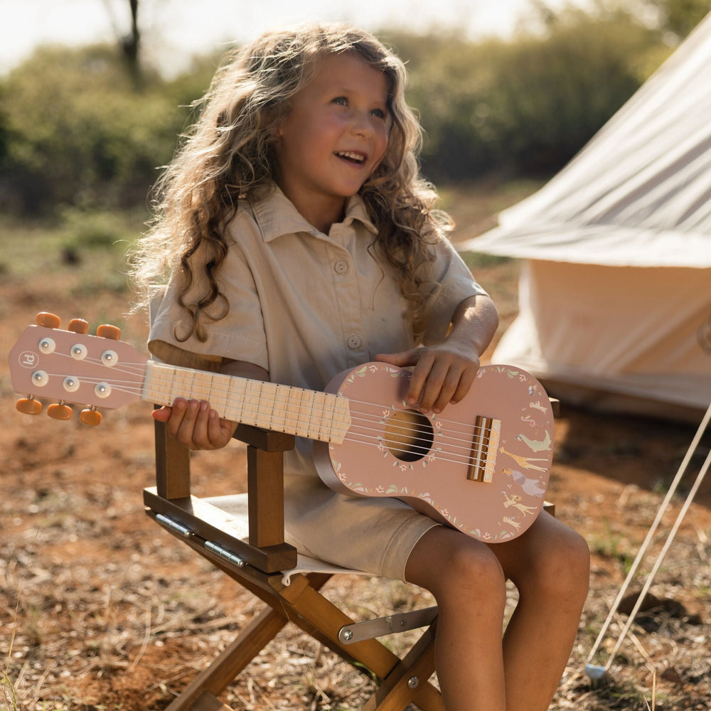 Kind speelt buiten op de roze Little Dutch Safari Friends houten gitaar