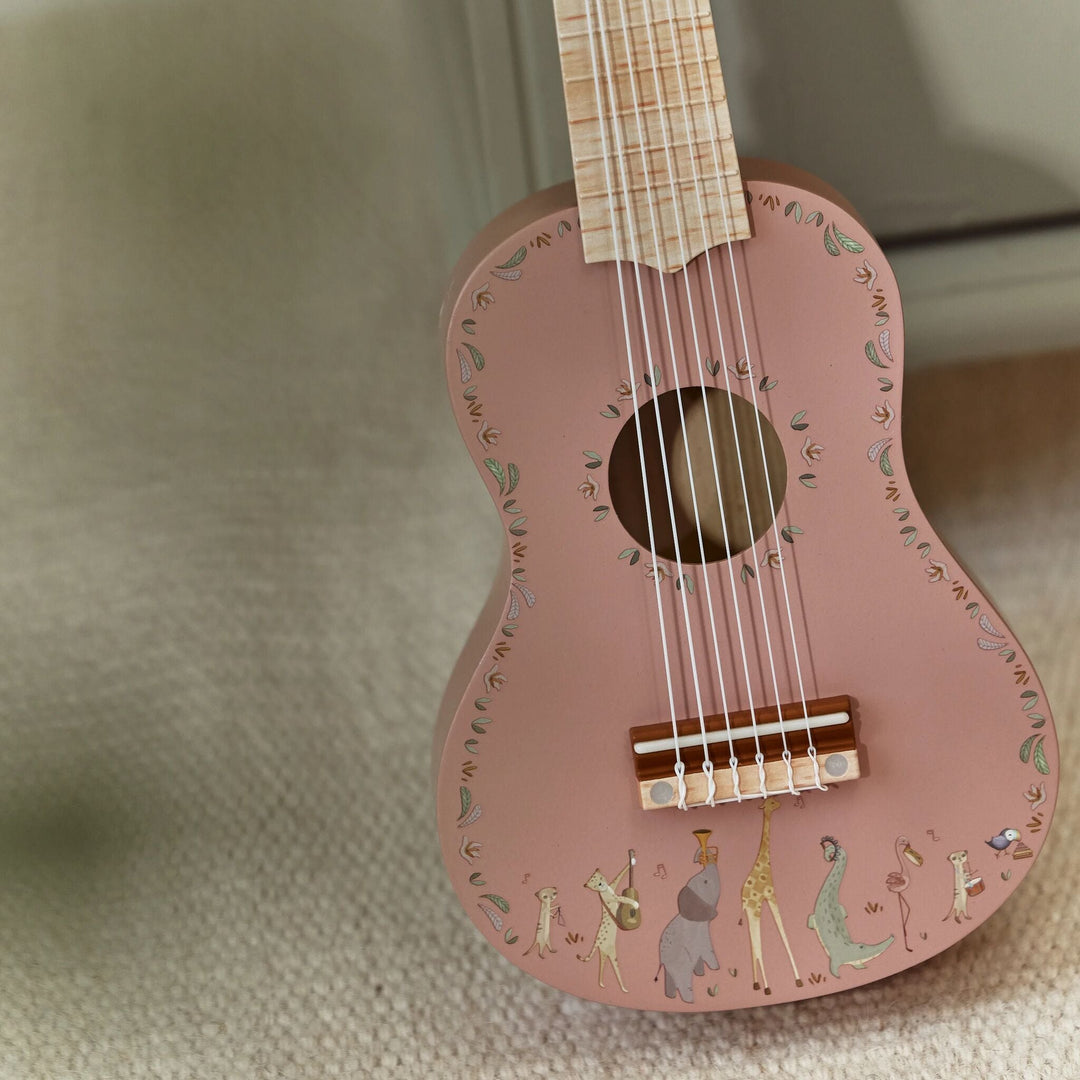 Close-up van klankkast en zes snaren van de roze Little Dutch Safari Friends gitaar