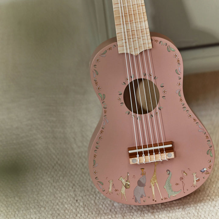 Close-up van klankkast en zes snaren van de roze Little Dutch Safari Friends gitaar