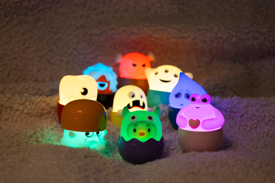 Verschiedene farbige Eggy Monsters-Lichter leuchten auf einem Teppich.