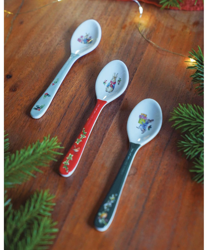Rode Peter Rabbit kerstlepel naast blauwe en groene lepels op een houten tafel