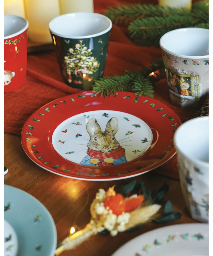 Rood Peter Rabbit kerstbord met ander servies op een houten kersttafel